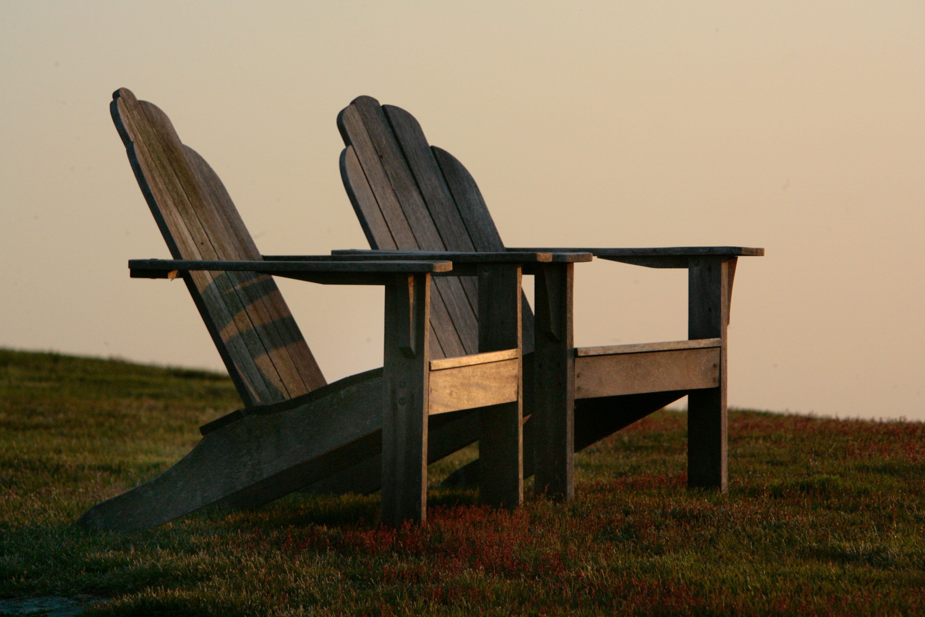Two wooden chairs overlooking a quiet landscape at sunset